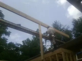 Carpenter setting a ridge beam over a new addition frame — Ice Dam Removal by Roofing Brothers in Nixon