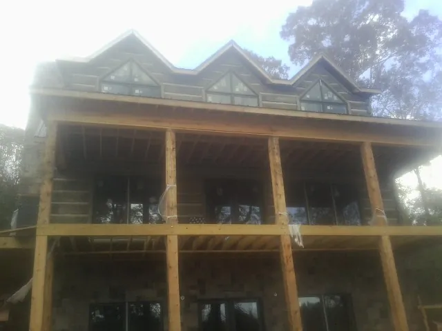 Dormers and porch framing on a large log home under construction — Roof Coating work by our crew in Nixon